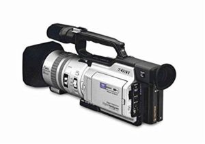 A profile view of the vintage Sony DCR-VX2000 MiniDV camcorder, highlighting its large optical lens barrel, top handle with integrated hot shoe, side-mounted flip-out LCD screen, and built-in stereo microphone.