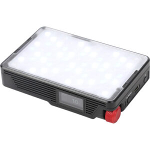 An angled top-down shot of a compact, square Aputure MC Pro RGBW LED light panel with its diffusion panel illuminated, casting a soft white light.