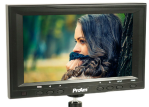 Pro Am 7-inch analog video monitor displaying a cinematic color portrait of a person with long hair against a blurred backdrop.